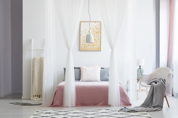 White chair in canopy bedroom