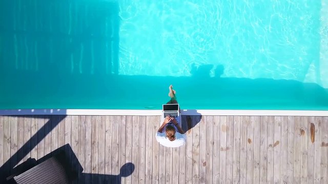 Top view young man enjoy swimming pool use laptop sunny summer drone footage