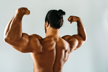 Rare view of a male bodybuilder in studio, showing biceps on hands
