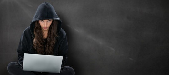 Composite image of young female hacker using laptop while