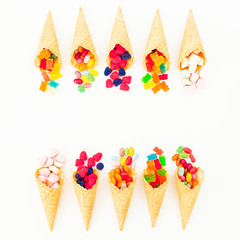 Waffle cones with colorful bright candy on white background. Flat lay, top view