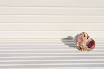 photography image of fresh white garlic bulb and cloves on bright white wood background taken on South coast England UK