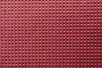 Red plastic material with symmetric square holes, abstract texture