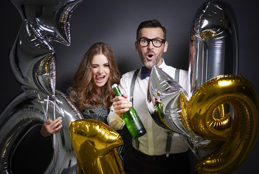 Cheerful couple with champagne and ballons celebrating .