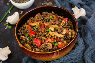 Delicious lentils with pepper and mushrooms on dark background