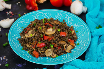 Delicious lentils with pepper and mushrooms on dark background