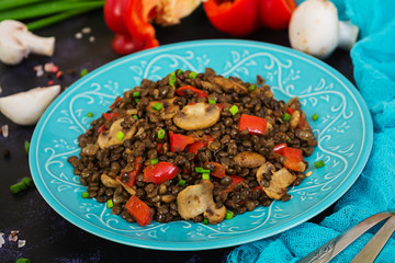 Delicious lentils with pepper and mushrooms on dark background