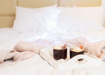 Breakfast in bed for two - tray with cup of coffee and sweet marshmallows, cozy hygge home style