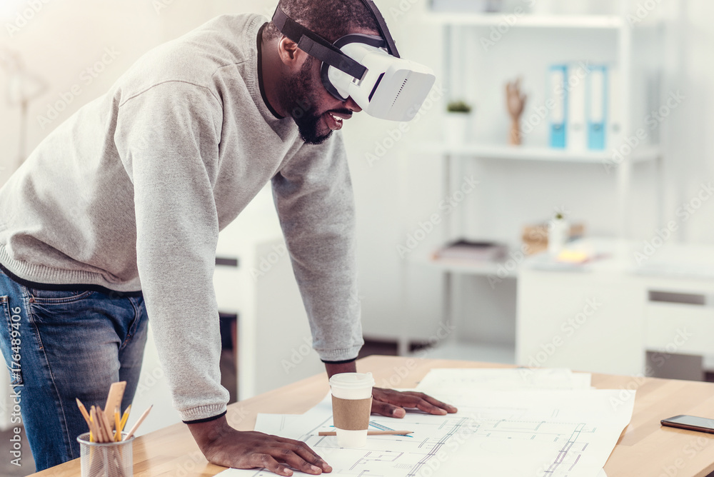 Wall mural Millennial engineer trying on VR goggles at work