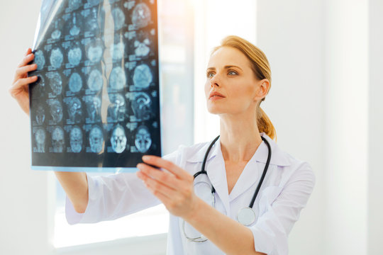 Serious female radiologist examining MRI scan image