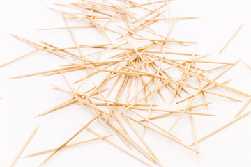 Close-up of a pile of wooden toothpicks on white background