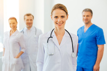 Fototapeta premium Positive minded female practitioner with stethoscope posing for camera