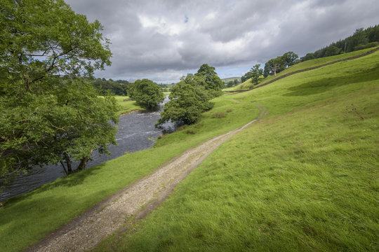 Characteristic English Landscape green field and the river Wharfe with path leading into the countryside