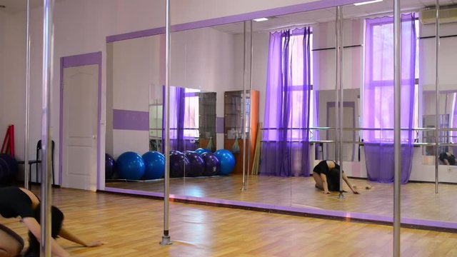Girl training pole dance in fitness club.