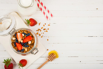 homemade granola in a glass jar on a white table. Healthy food.
