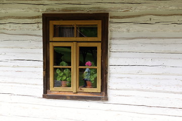 Obraz na płótnie Canvas Wooden window on the wooden wall with flowers inside