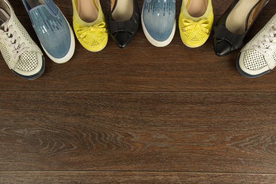 Four pairs of women's shoes of white, yellow, blue and black on the brown floor