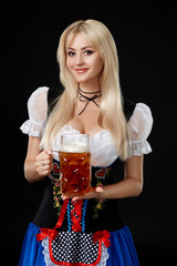 Young sexy woman wearing a dirndl with beer mug on black background.