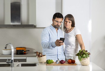 couple looking at a mobile phone in a kitchen