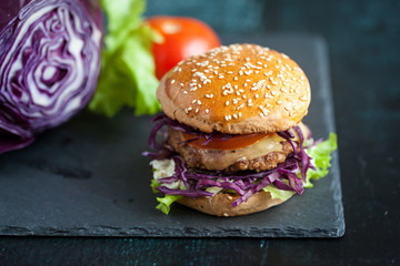 Burger with purple cabbage over black textured board 