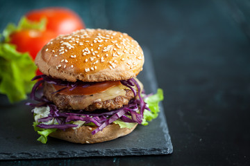 Burger with purple cabbage over black textured board 