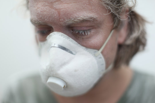 handyman at work, sanding walls while using face mask, drywall construction