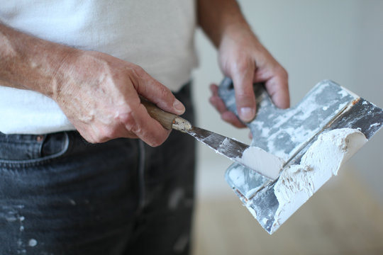 handyman at work, working with sand plaster filler on stopping knife , house painter