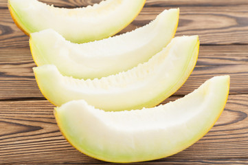 Four slices of fresh ripe yummy melon on old rustic brown wooden background