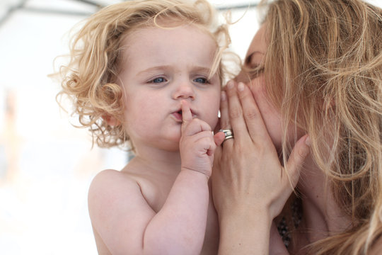 mother and child sharing a secret, whispering, scandinavian child