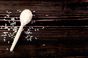 Raw and uncooked white rice in wooden spoon on wood background with copyspace for your text. Healthy eating and food background. Top view, flat, overhead