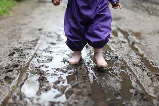 toddler in rain clothes walking in mud and rain puddle, autumn break