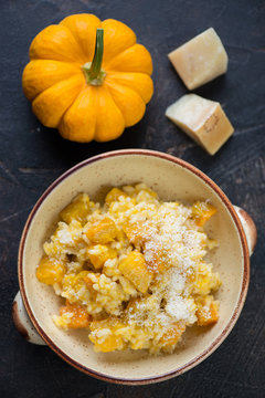 Risotto with pumpkin and parmesan, above view on a dark brown stone background