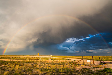 Sunset rainbow amid dramatic clouds over New Mexico desert landscape, USA