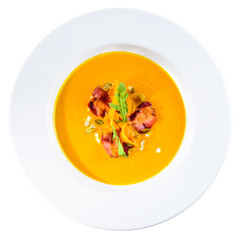 Delicious and appetizing pumpkin cream soup with chips in a white plate isolated on white background. Autumn menu in an Italian restaurant. Photo for menu design, top view, flat, overhead