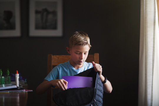 Boy Packing Backpack With School Stationery Supplies