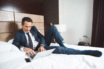 businessman on bed using laptop