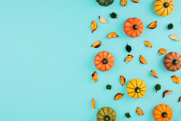 Decorative pumpkins on trendy blue background with fall leaves.