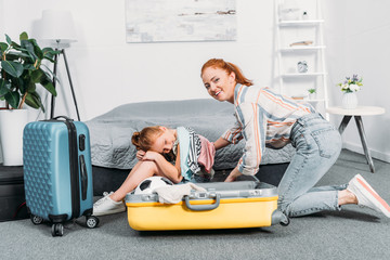 mother and daughter packing clothes for trip