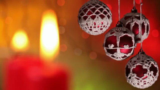 Lighting the christmas spirit - camera refocusing from baubles to burning candles against blurry blinking xmas lights background
