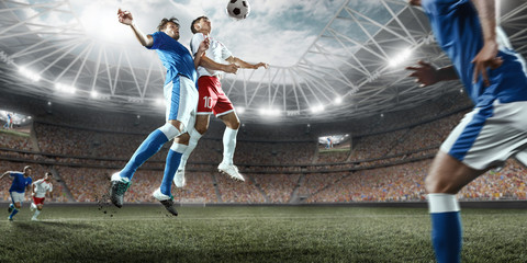 Soccer players performs an action play on a professional stadium. Two football teams fighting for...