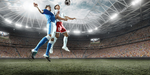 Soccer players performs an action play on a professional stadium. Two football teams fighting for...