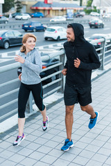 sportswoman and sportsman jogging in city