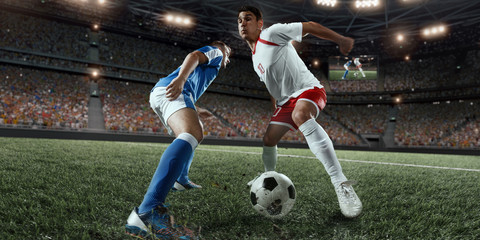 Soccer players performs an action play on a professional stadium. Two football teams fighting for...