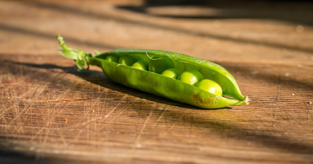 Pods of green organic peas with leaves on wooden table, Healthy food