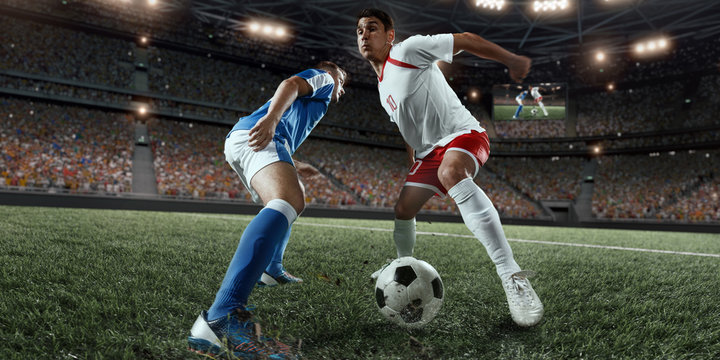 Soccer players performs an action play on a professional stadium. Two football teams fighting for the ball. Players wears unbranded sport uniform.