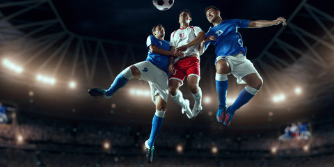 Soccer players performs an action play on a professional stadium. Two football teams fighting for the ball. Players wears unbranded sport uniform. © Alex