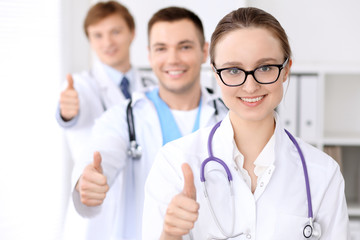 Fototapeta premium Happy doctor woman with medical staff at the hospital, thumbs up