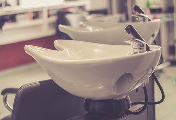 Beauty salon interior - a row of hair washing sinks - white washbasins for hairdresser