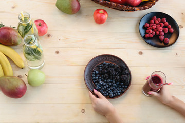 woman with detox drink and berries on plate
