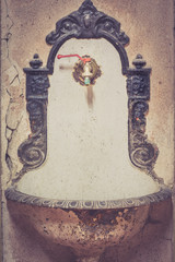 Closeup of an vintage white metal drinking fountain attached on a white wall